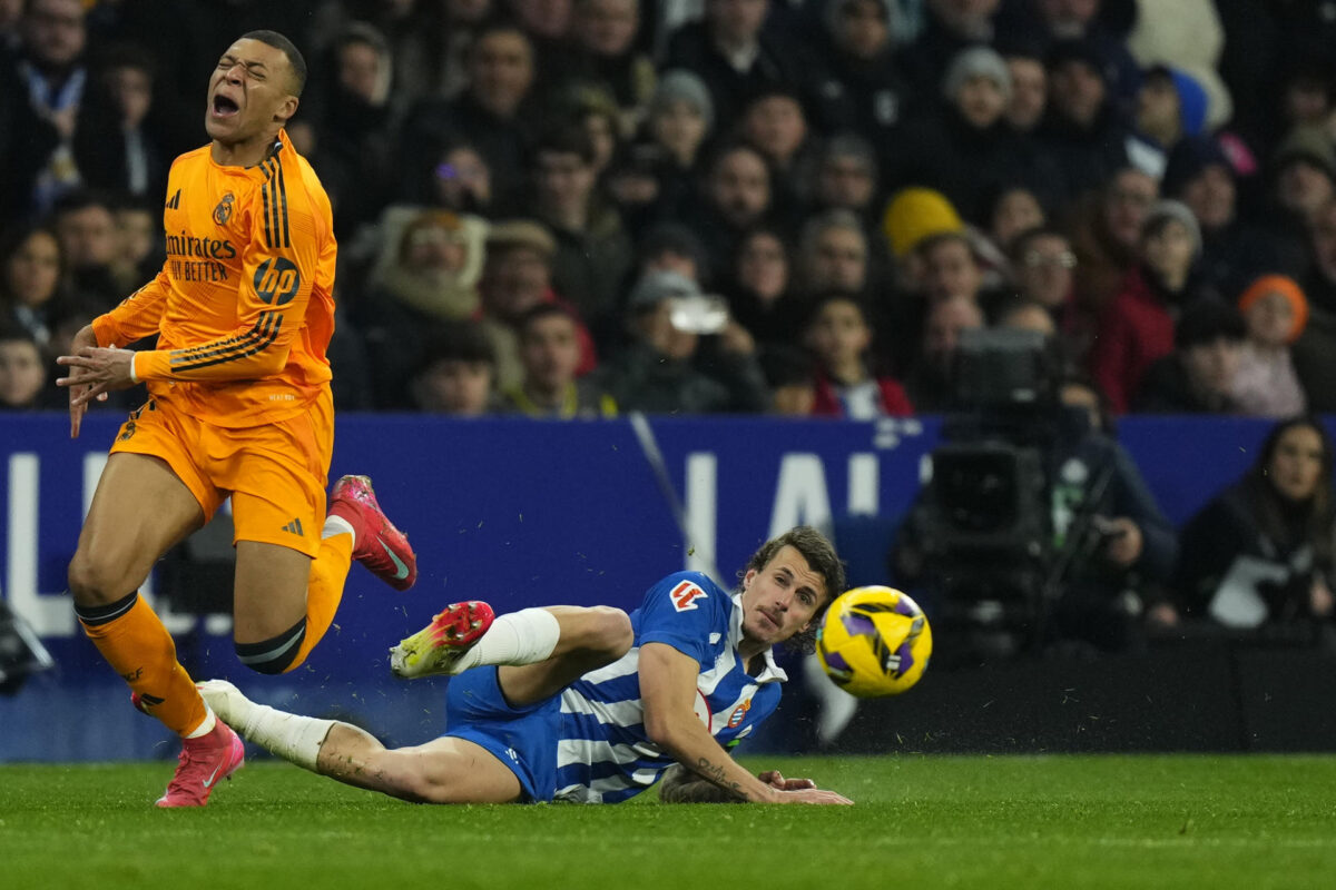 El delantero francés del Real Madrid, Kylian Mbappé (i) cae derribado durante el encuentro correspondiente a la jornada 22 de Laliga EA Sports que disputaron el Espanyol y Real Madrid en el RCDE Stadium. EFE / Siu Wu